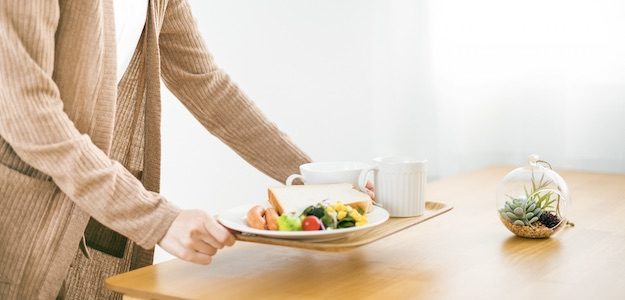 食事をテーブルに運ぶ人の写真